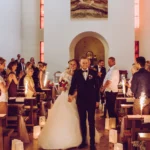 Braut und Bräutigam im Kirchgang beim Verlassen der Kirche, Gäste applaudieren, Ganzkörper, indoor