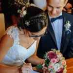 Braut unterschreibt auf Standesamt, Hochzeitsstrauß, Bräutigam, Brustbild, indoor