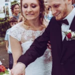 Braut und Bräutigam schneiden Hochzeitstorte an Brustbild outdoor