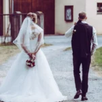 Paarshooting, Braut und Bräutigam schlendern von Kamera weg Hochzeitsstrauß von hinten Ganzkörper outdoor