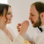 Braut und Bräutigam probieren gegenseitig Hochzeitstorte Brustbild indoor